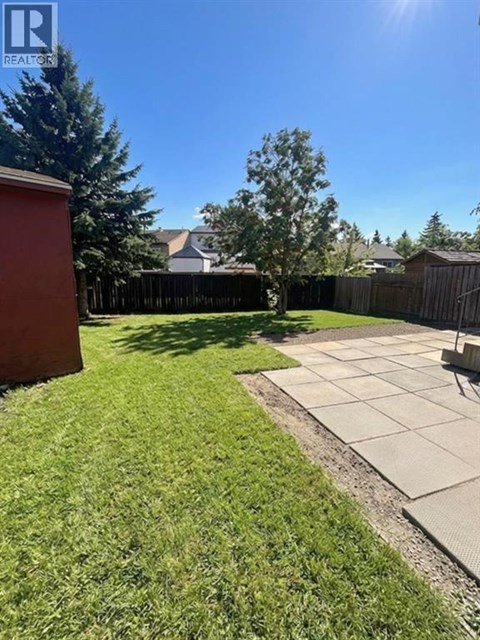 A backyard with a green lawn and a concrete patio.