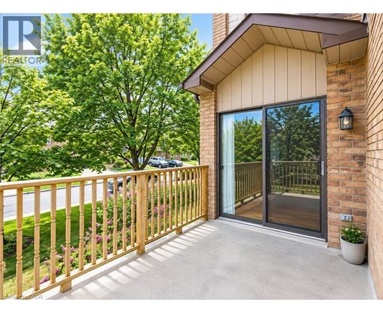 A balcony with a wooden railing and a glass door leading to a patio.