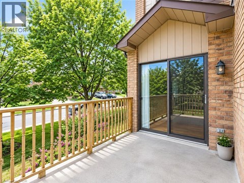 A balcony with a wooden railing and a glass door leading to a patio.