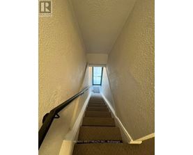 A stairway with a black handrail leading to a door at the top.