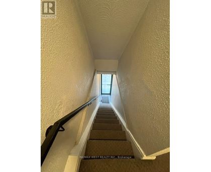 A stairway with a black handrail leading to a door at the top.
