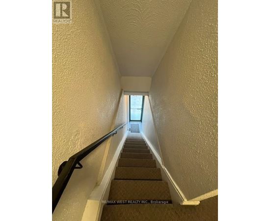 A stairway with a black handrail leading to a door at the top.