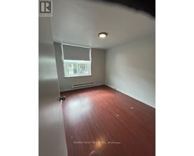 A room with a window and a wooden floor.