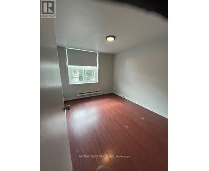A room with a window and a wooden floor.
