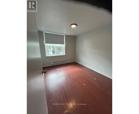 A room with a window and a wooden floor.