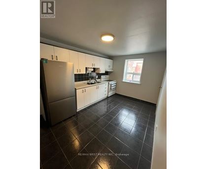 A kitchen with black tile flooring and white cabinets.