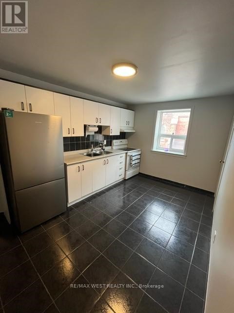 A kitchen with black tile flooring and white cabinets.