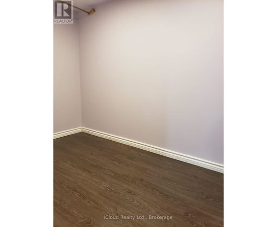A room with wooden flooring and white walls.