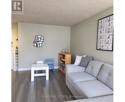 A living room with a grey couch, a white table, and a wall with a picture of a family.