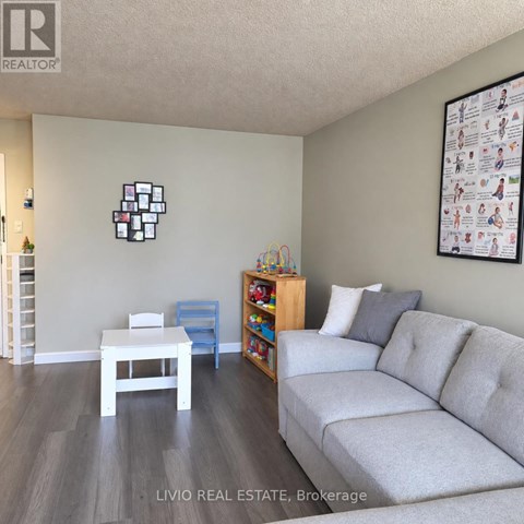A living room with a grey couch, a white table, and a wall with a picture of a family.