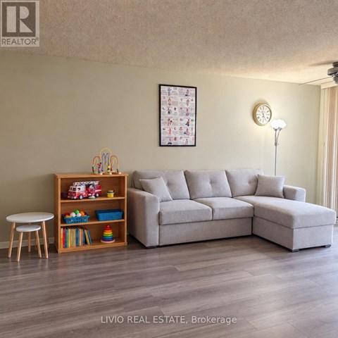 A living room with a grey sofa, a wooden shelf with toys, and a white table.