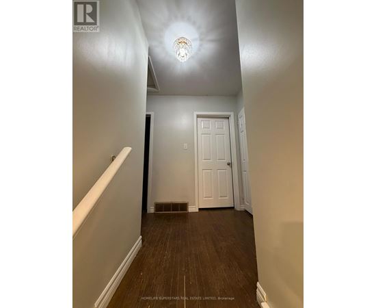 A hallway with a white door and wooden floors.