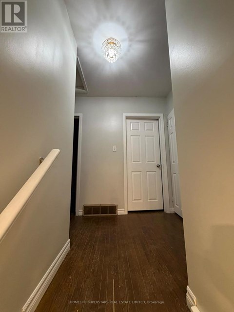A hallway with a white door and wooden floors.