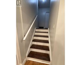 A staircase with white railings and brown steps.