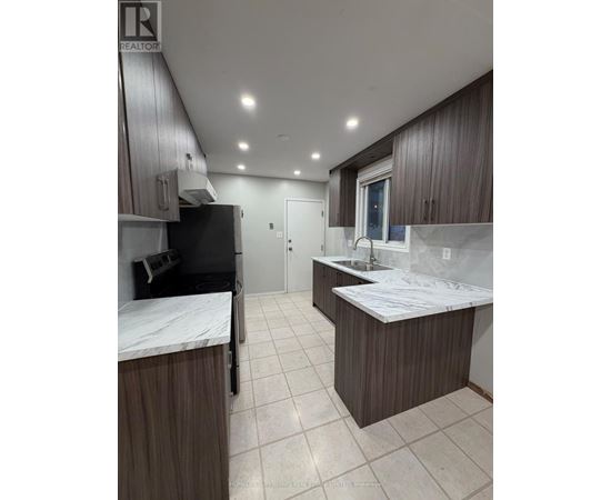 A kitchen with brown cabinets and a black fridge.