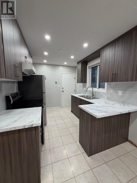 A kitchen with brown cabinets and a black fridge.