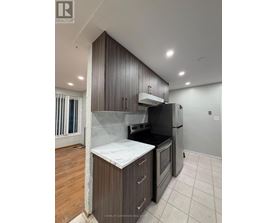 A kitchen with a black refrigerator and wooden cabinets.
