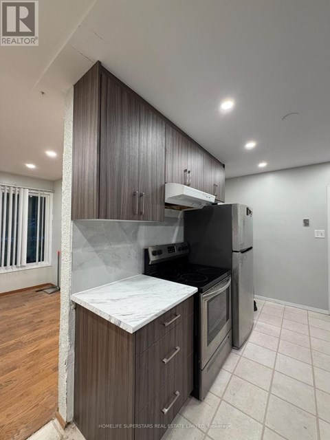 A kitchen with a black refrigerator and wooden cabinets.