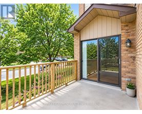 A balcony with a wooden railing and a glass door leading to a backyard.