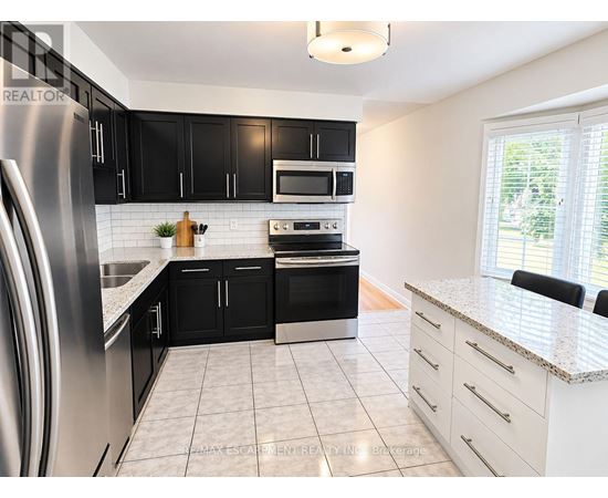 A modern kitchen with black cabinets and stainless steel appliances.