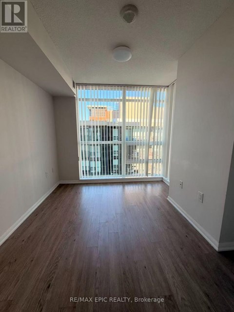 A room with wooden floors and a window with blinds.