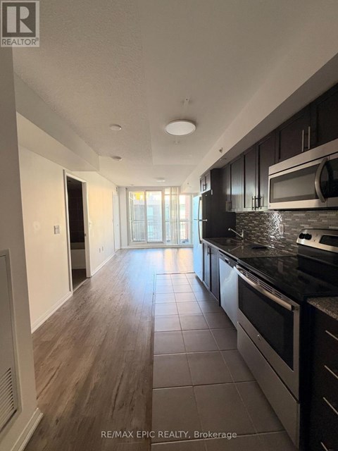 A modern kitchen with dark wood cabinets and stainless steel appliances.