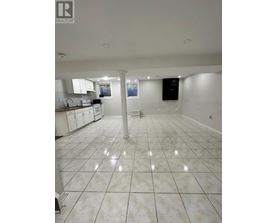 A large, empty kitchen with white tile flooring and white cabinets.