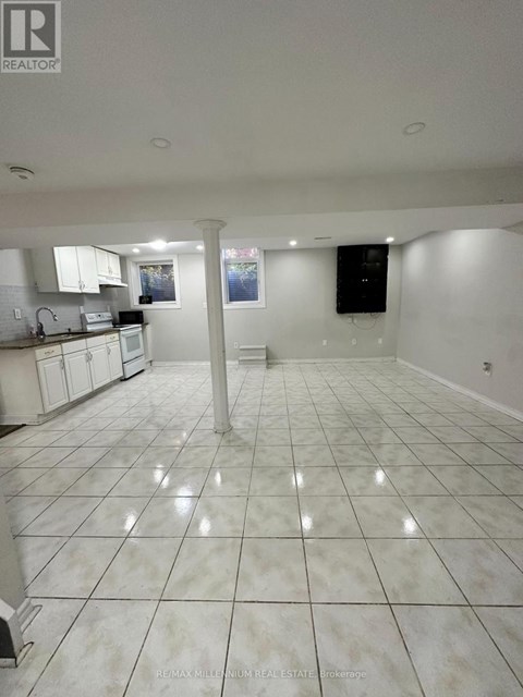 A large, empty kitchen with white tile flooring and white cabinets.