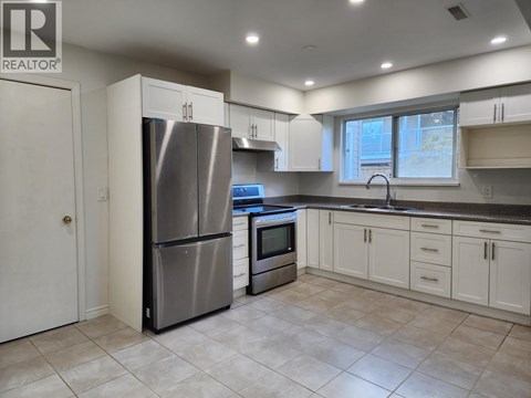 A kitchen with a refrigerator, oven, and microwave.