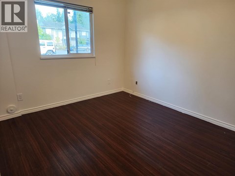 A room with a window and wooden flooring.