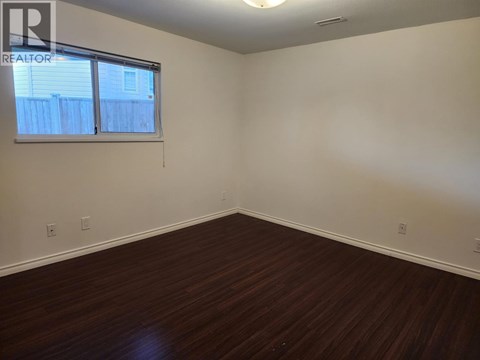 A room with a window and wooden flooring.