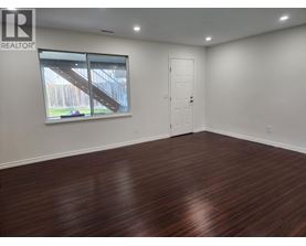 A room with wooden flooring and a window showing an outdoor staircase.