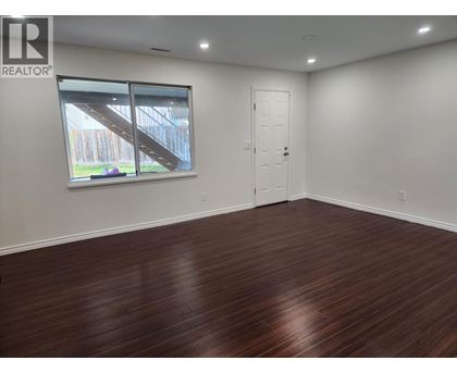 A room with wooden flooring and a window showing an outdoor staircase.