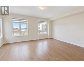 A spacious room with wooden flooring and two windows.