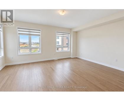 A spacious room with wooden flooring and two windows.