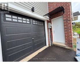 A black garage door is closed and there is a white door to the right of the garage.