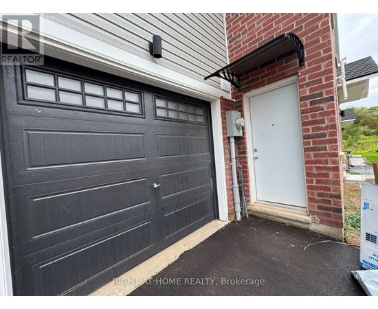A black garage door is closed and there is a white door to the right of the garage.