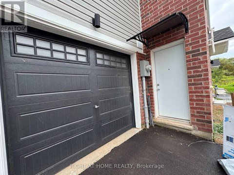 A black garage door is closed and there is a white door to the right of the garage.