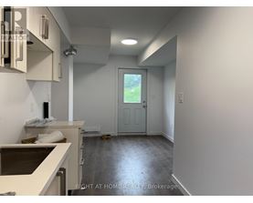 A room with a door leading outside and a counter on the left.