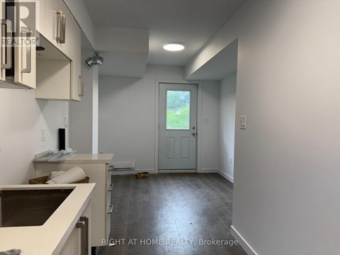 A room with a door leading outside and a counter on the left.