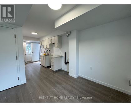 A kitchen area with a white fridge, sink, and cabinets.