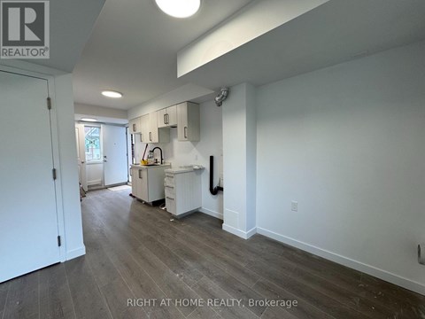A kitchen area with a white fridge, sink, and cabinets.