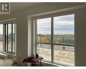 A room with a table and chairs in front of a large window overlooking a parking lot.