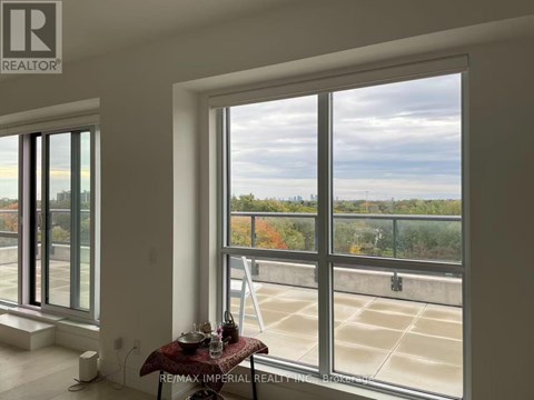 A room with a table and chairs in front of a large window overlooking a parking lot.