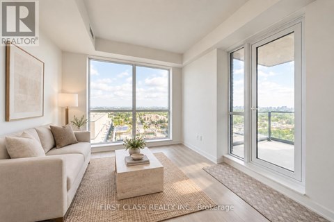 A well-lit living room with a view of the cityscape outside the large windows.