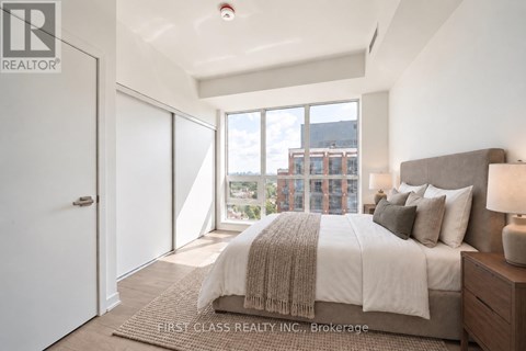 A bedroom with a large bed and a view of a cityscape through the window.