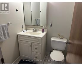 A bathroom with a toilet, sink, and mirror.