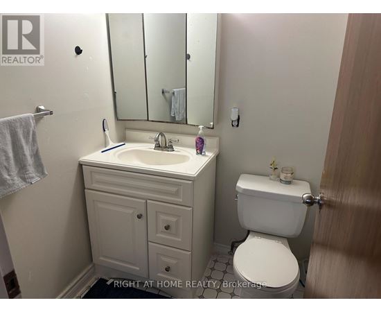 A bathroom with a toilet, sink, and mirror.