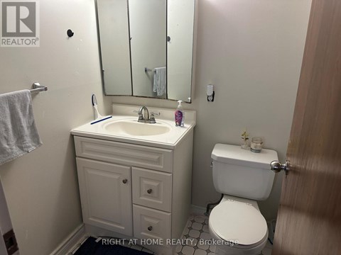 A bathroom with a toilet, sink, and mirror.