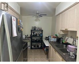 A kitchen with a refrigerator, sink, and a fan.